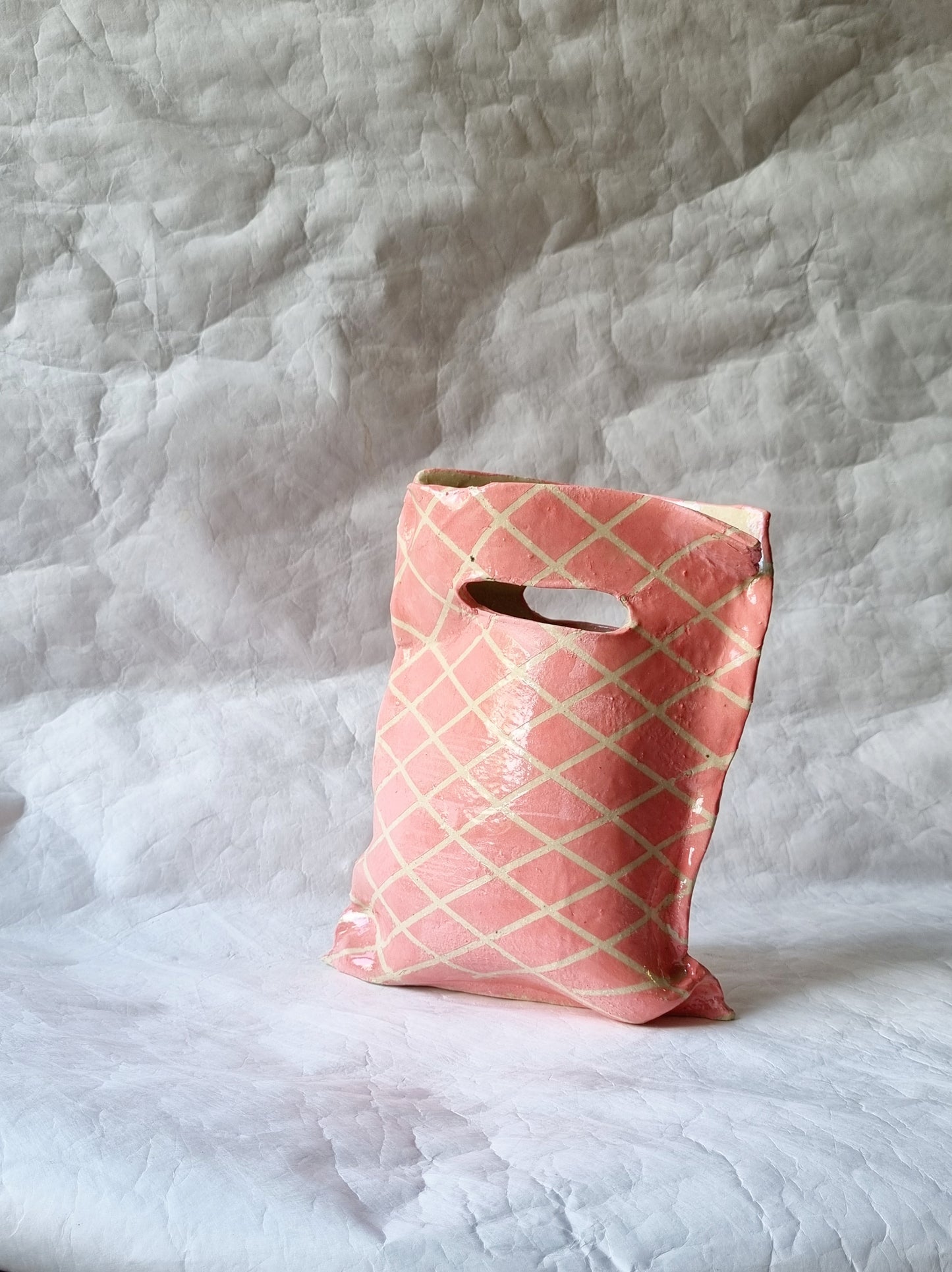 A hand-built stoneware ceramic vessel resembling a plastic shopping bag, a sculptural art piece exploring modern consumption by foRM of Mondays.