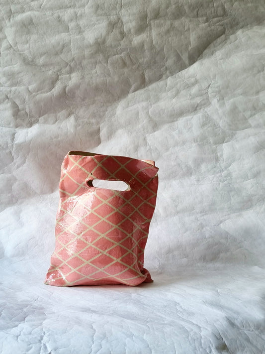 A hand-built stoneware ceramic vessel resembling a plastic shopping bag, a sculptural art piece exploring modern consumption by foRM of Mondays.