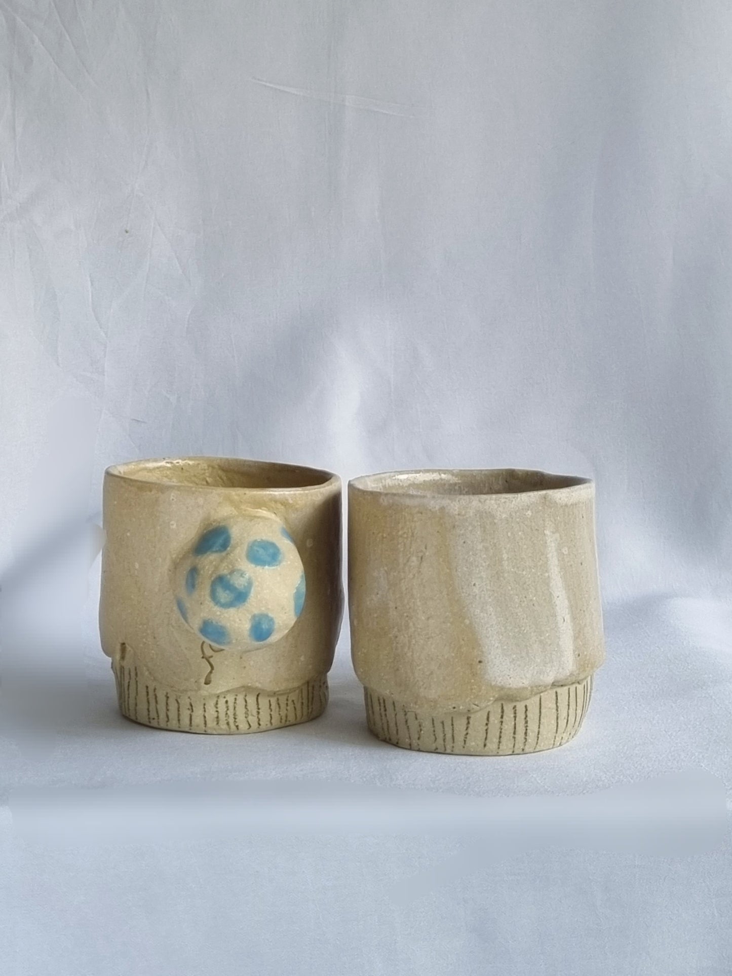 Two whimsical ceramic cups on a white background