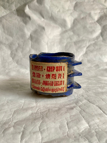 Handbuilt ceramic cup featuring the “Danger-Keep out” construction sites signage on a a surface 