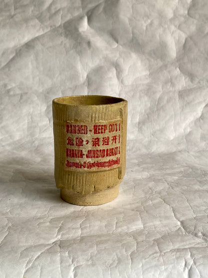 Handbuilt ceramic tumbler featuring “Danger- Keep out” signage 