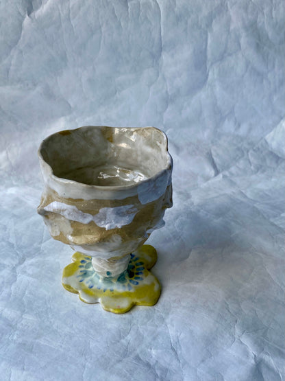 Small ceramic cup with textured surface and yellow flower base